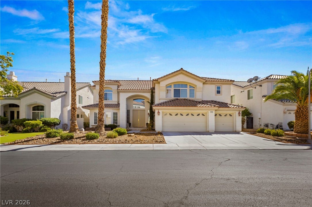 Stately palm trees flank the driveway of this elegant two-story estate with stucco exterior and tile roofing.