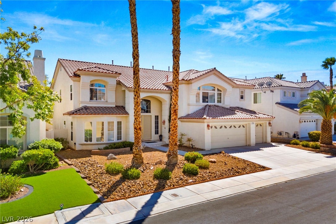 Stately palm trees flank the driveway of this classic stucco two-story estate.