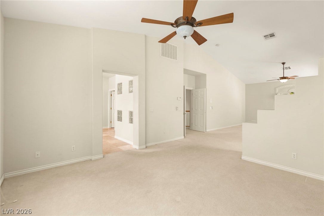 Vaulted ceilings and soft carpeting define this versatile sitting area, in the ultra-spacious primary bedroom.