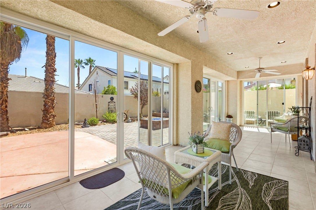 Sunlight streams through expansive sliding glass doors into a tiled sunroom opening to the backyard.