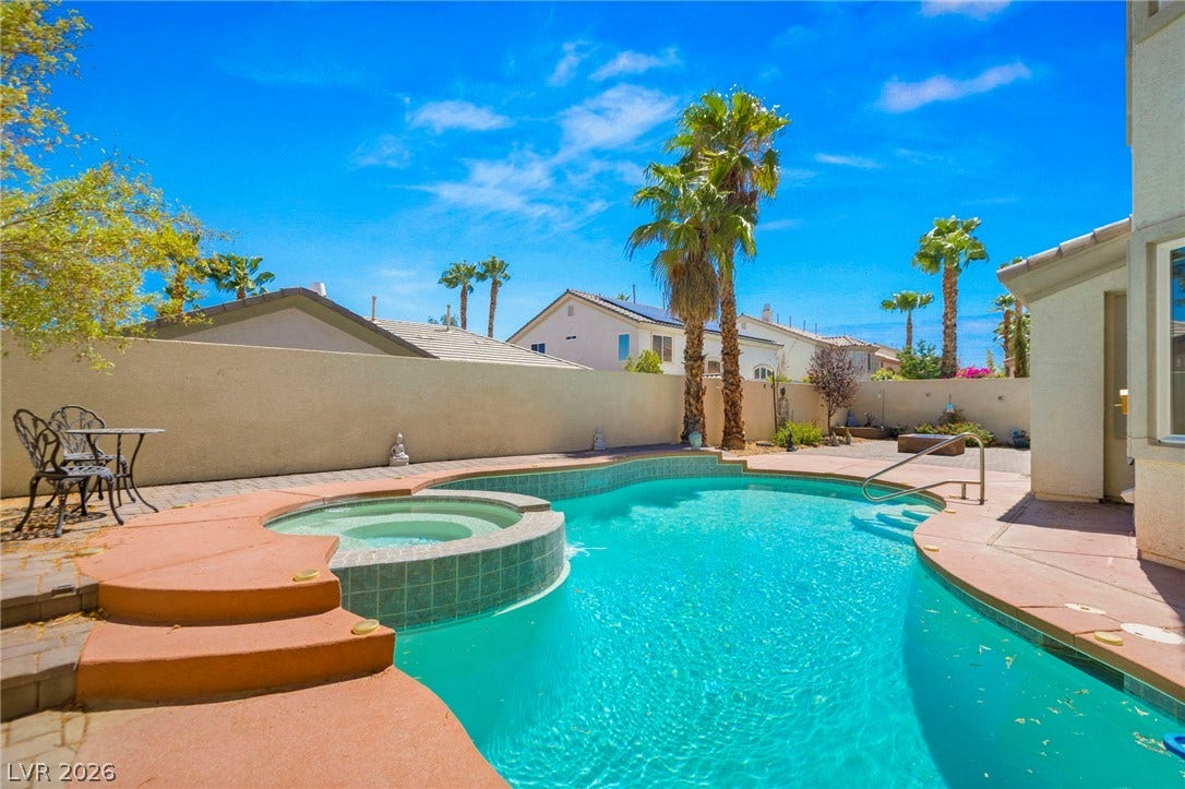 An inviting backyard pool and spa are enclosed by a privacy wall.