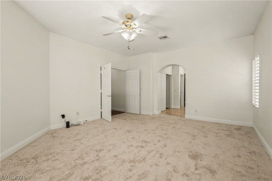 1424 Clipperton Avenue, Henderson, NV 89074 Soft carpeting underfoot anchors a spacious bedroom featuring an arched doorway and clean design.