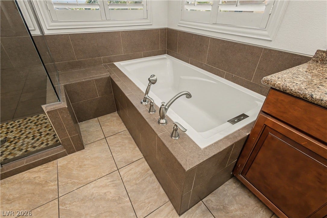 1424 Clipperton Avenue, Henderson, NV 89074 Earth-toned tile surrounds a deep soaking tub next to a glass-enclosed shower.