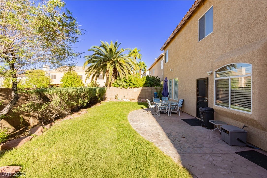 1424 Clipperton Avenue, Henderson, NV 89074 An arched window overlooks a flagstone patio bordering a neat lawn under clear blue skies.