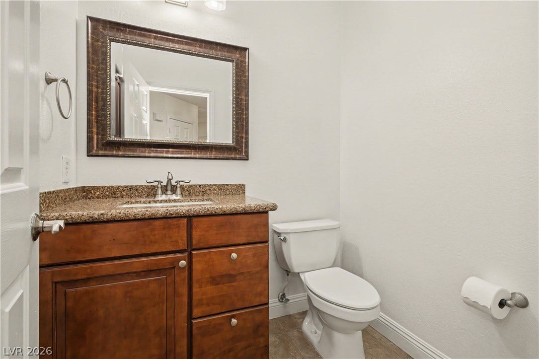 1424 Clipperton Avenue, Henderson, NV 89074 Polished granite countertops complement warm wood cabinetry in this classic powder room.