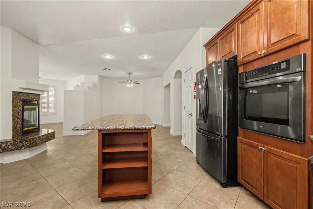 1424 Clipperton Avenue, Henderson, NV 89074 Rich wood cabinetry and stone countertops anchor this open kitchen flowing into the living area.