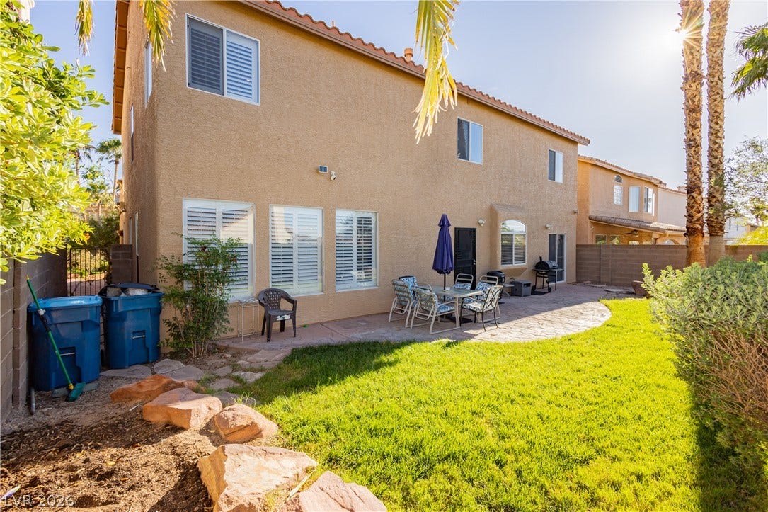 1424 Clipperton Avenue, Henderson, NV 89074 An inviting backyard features a green lawn bordered by a paved patio.