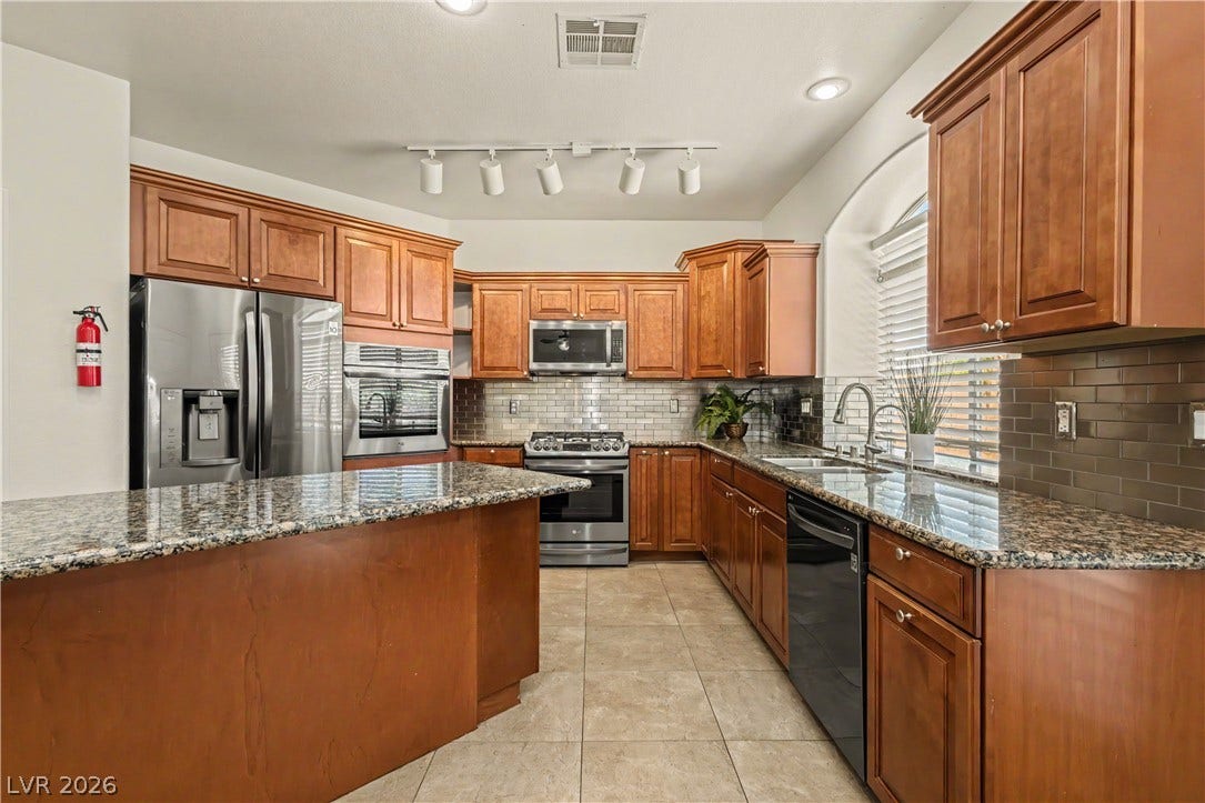 1424 Clipperton Avenue, Henderson, NV 89074 Rich wood cabinetry pairs with polished granite countertops and tile flooring in this classic kitchen.