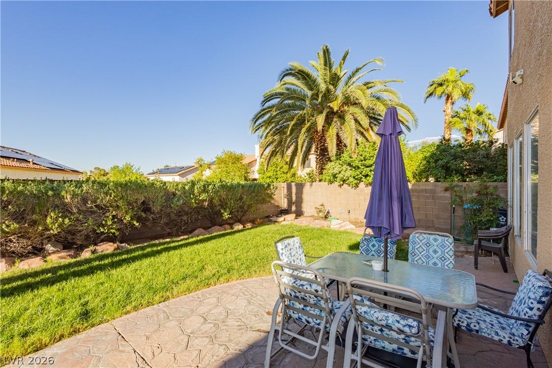 1424 Clipperton Avenue, Henderson, NV 89074 Palm trees frame a textured patio and grassy lawn in this private backyard retreat.