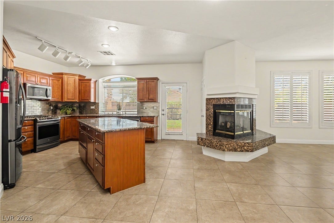 1424 Clipperton Avenue, Henderson, NV 89074 Granite countertops and a three-sided fireplace highlight this open tile-floored layout.