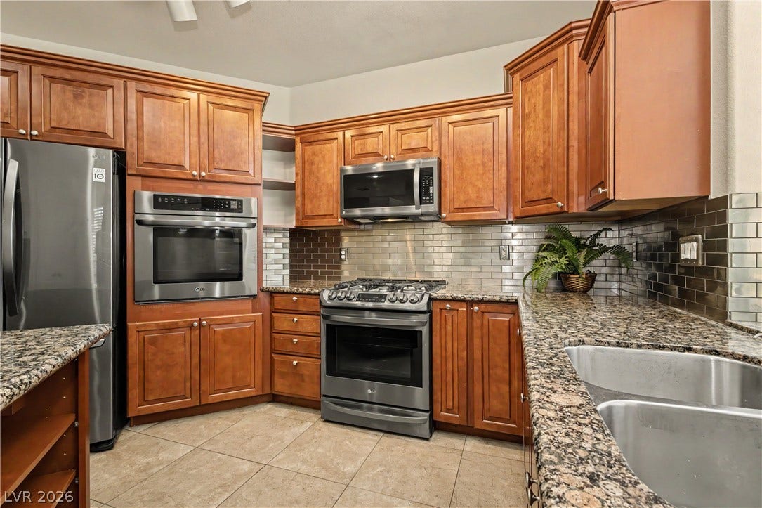 1424 Clipperton Avenue, Henderson, NV 89074 Rich wood cabinetry pairs with granite countertops and modern stainless steel appliances in this kitchen.