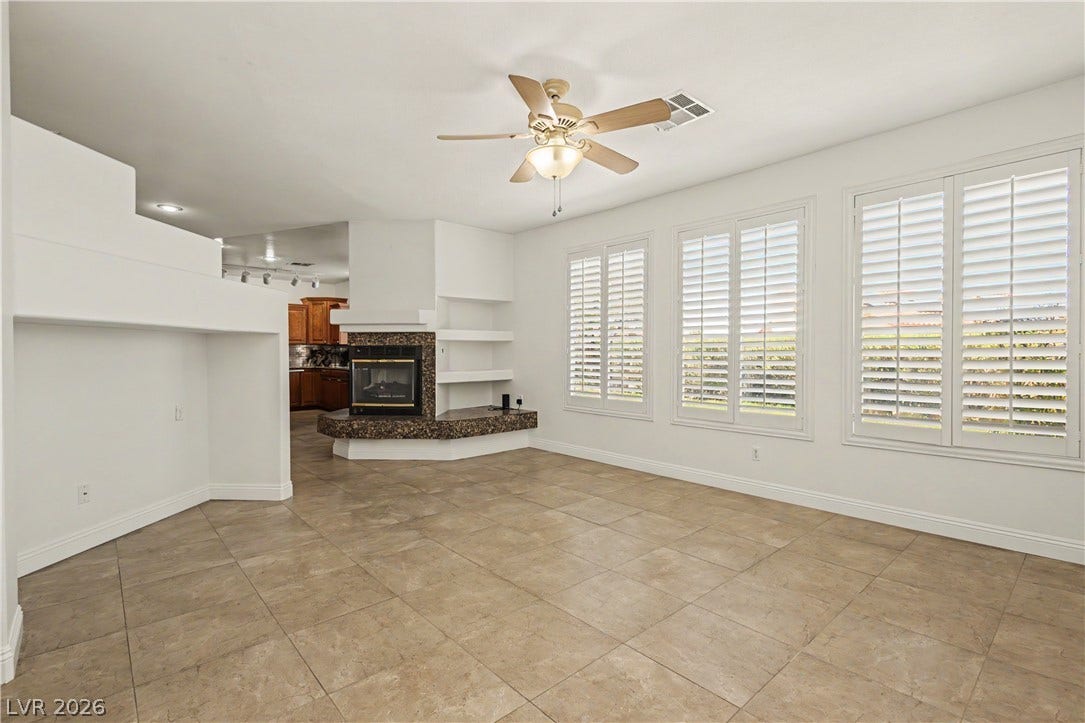 1424 Clipperton Avenue, Henderson, NV 89074 Tiled flooring and plantation shutters complement a built-in corner fireplace in this open living space.