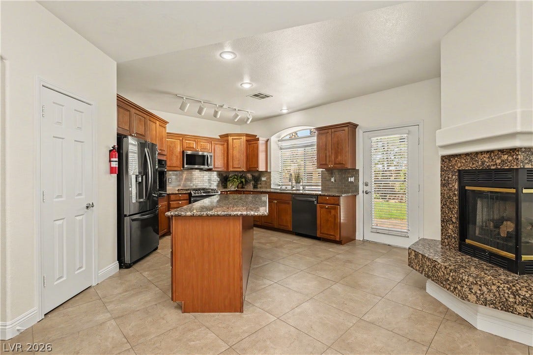 1424 Clipperton Avenue, Henderson, NV 89074 Warm wood cabinetry pairs with a stone fireplace and tiled flooring in this open kitchen.