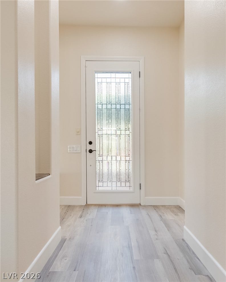 An inviting entryway features durable wood-look flooring and a decorative glass paneled front door.