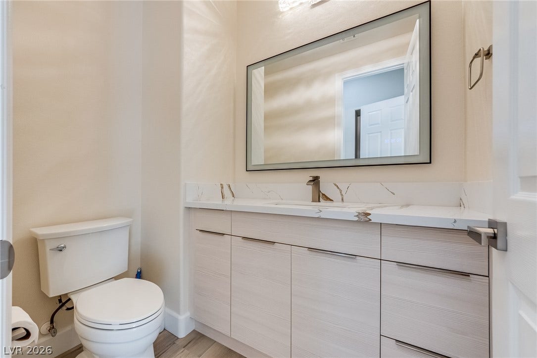 An elegant vanity with stone counters and modern cabinetry highlights this stylish half bath.