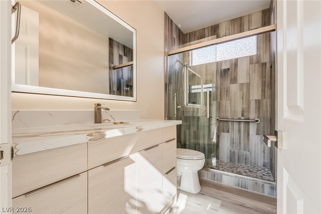 Modern stone counters and a fully tiled walk-in shower elevate this updated bathroom.