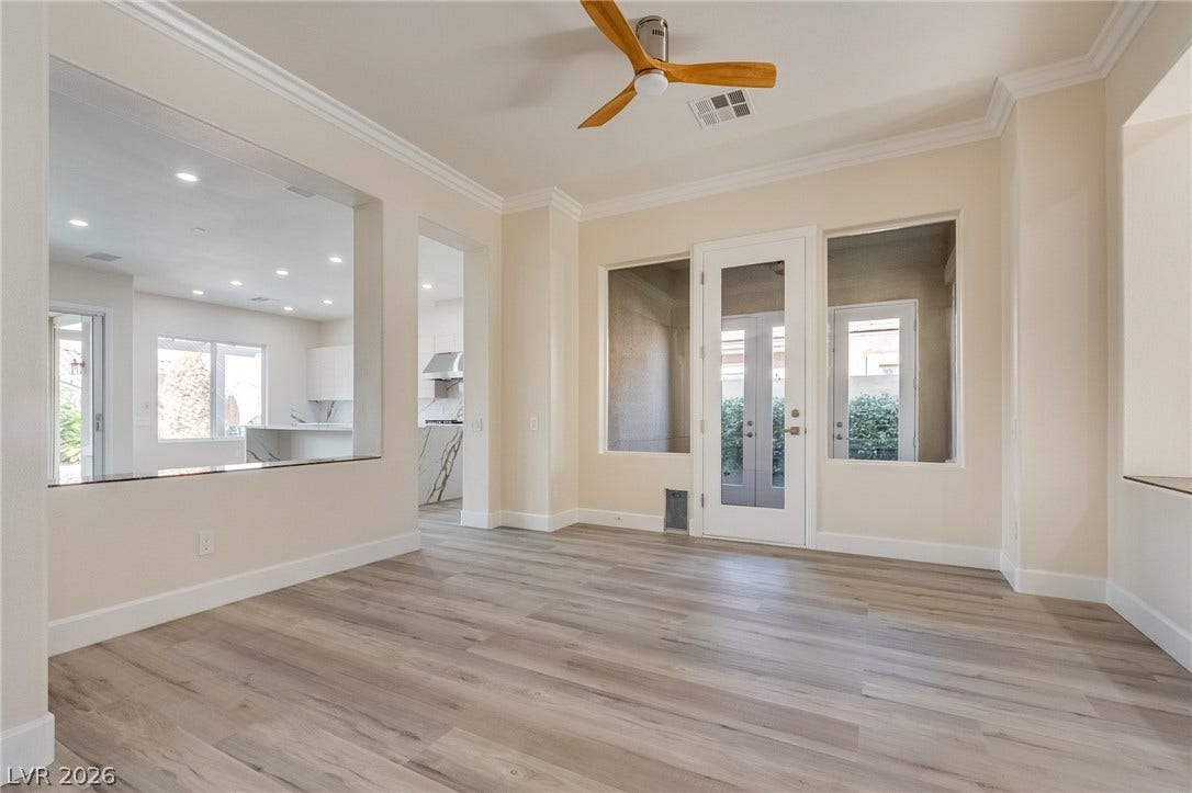 An open layout flows seamlessly across wood-look flooring toward a central glass door exit.