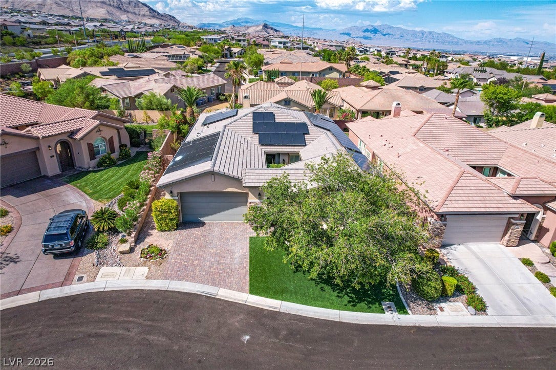 An aerial perspective showcases the tile roof integrated with solar panels and a paved driveway.