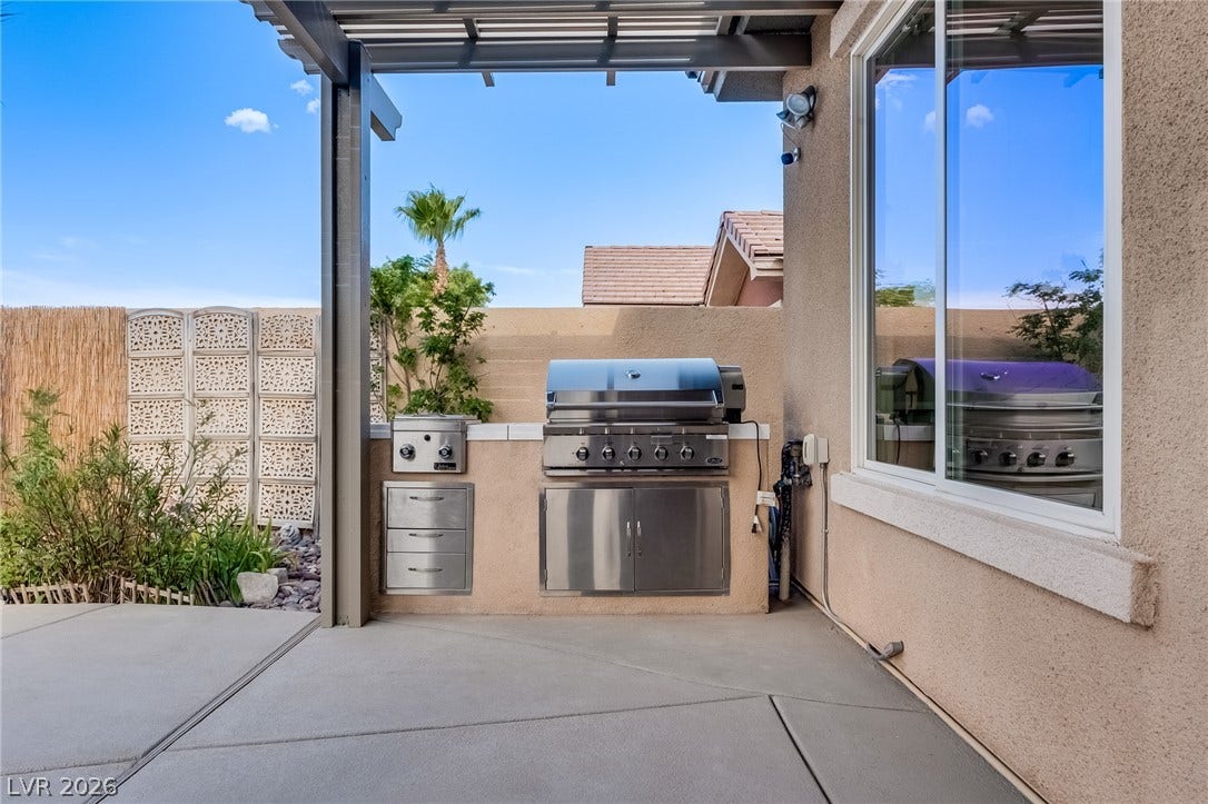 An outdoor cooking station integrates seamlessly alongside a covered concrete patio and stucco walls.