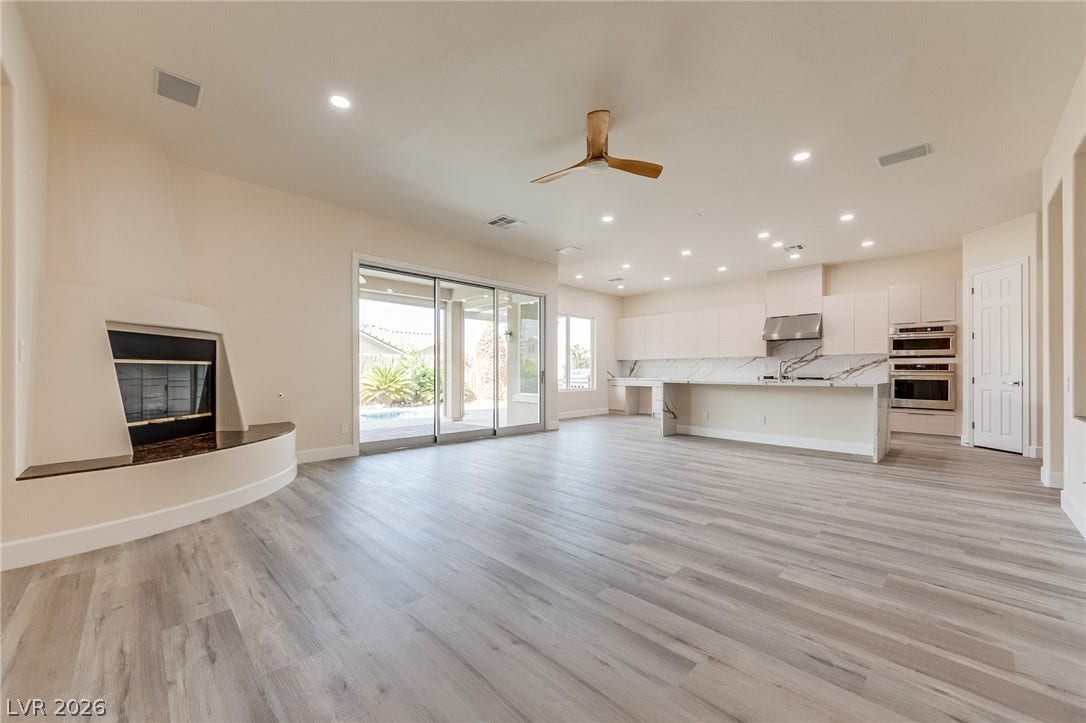 An open floor plan connects the living space and modern kitchen under high ceilings.