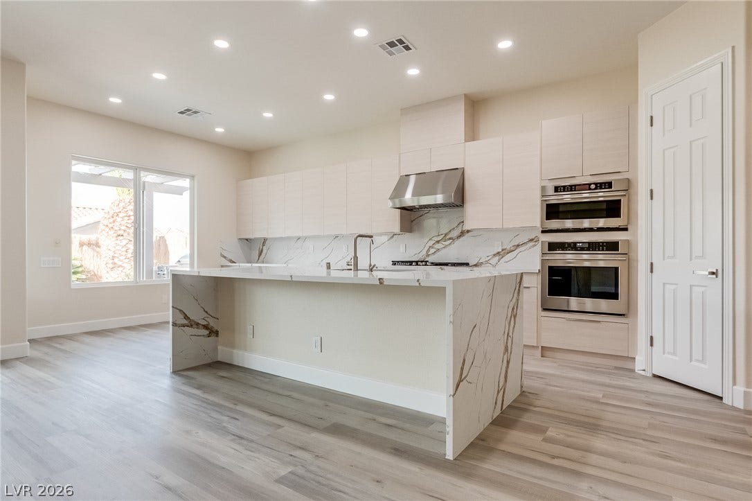 Recessed lighting illuminates wood-look flooring and a stone-clad island in this contemporary kitchen.