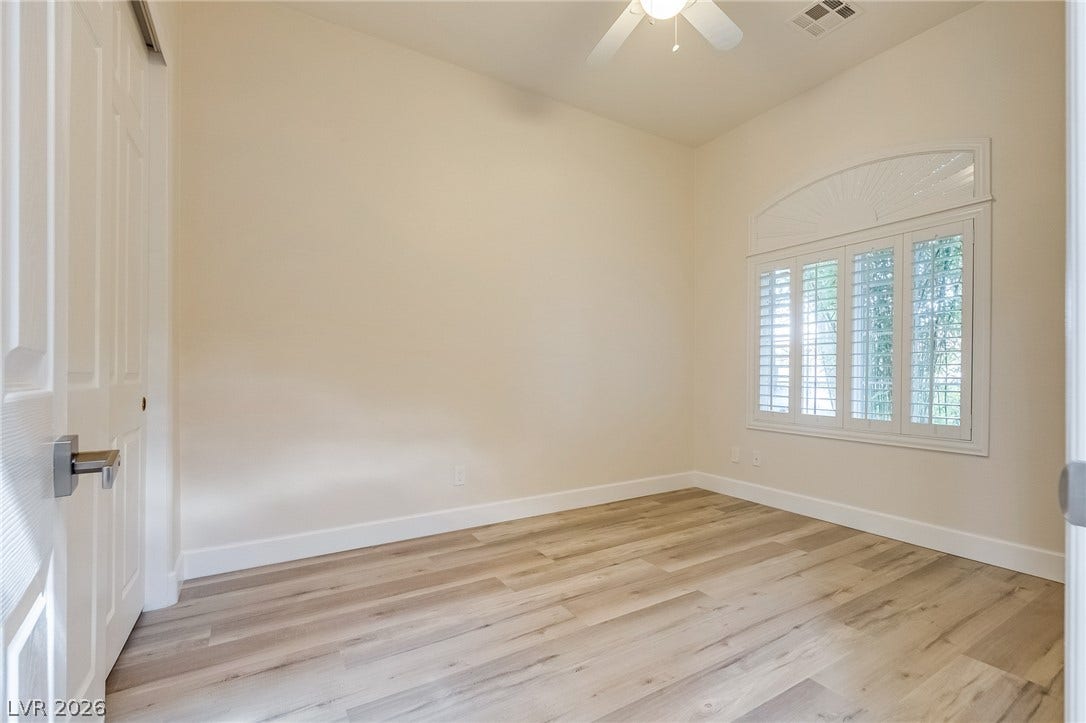 Smooth wood floors anchor this versatile room illuminated by an arched window with plantation shutters.