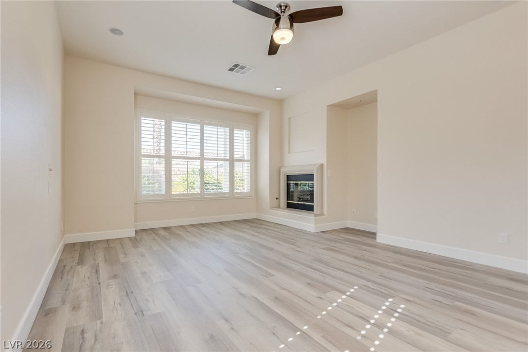 An inviting fireplace complements the light wood-style flooring and recessed alcoves.