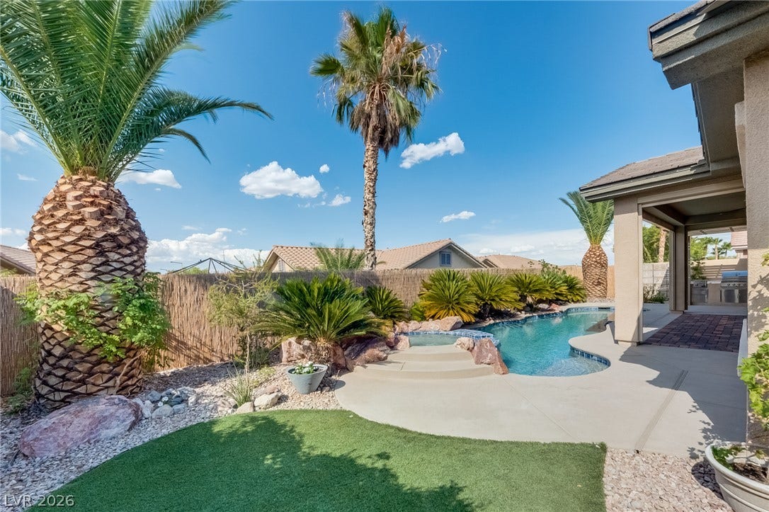 Lush palm trees frame a sparkling pool and spa in this private backyard oasis.