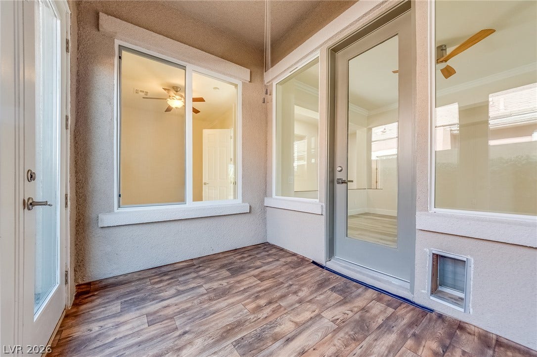 Rich wood-look plank flooring lines this covered porch with glass doors leading inside.