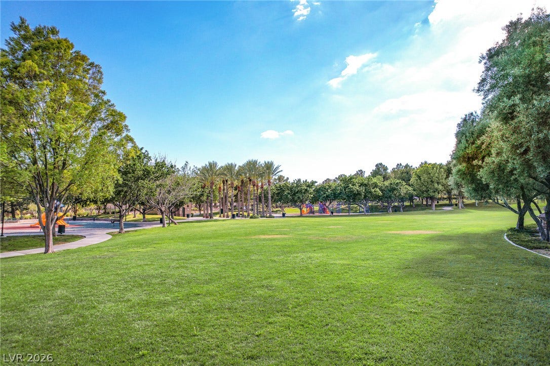 Mature trees frame a manicured green space complete with community playground facilities.