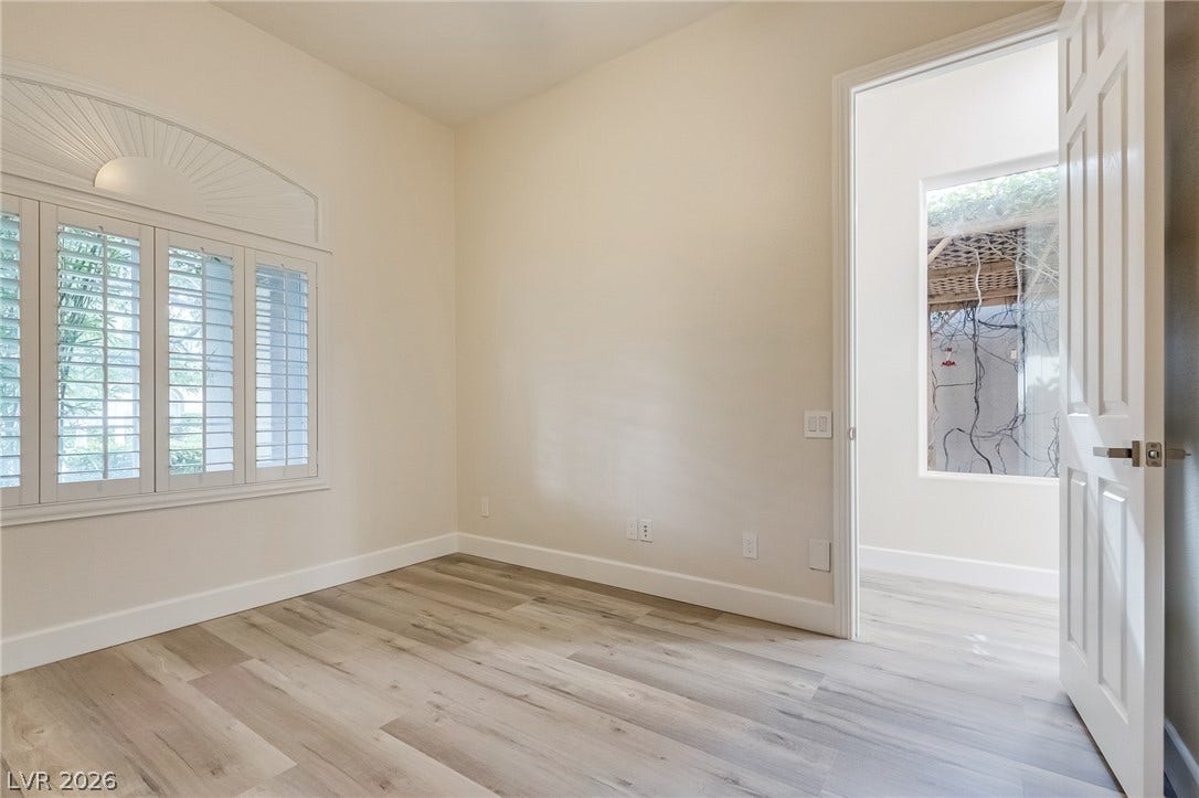 Gleaming wood-look floors anchor this versatile room featuring plantation shutters and an arched window detail.