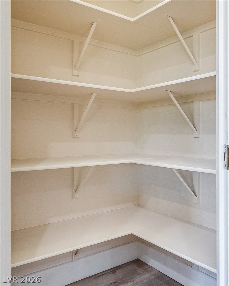 Generous wrap-around shelving optimizes storage space in this walk-in kitchen pantry.