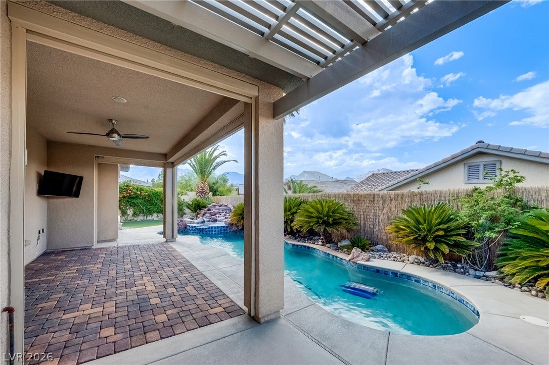 An inviting backyard oasis features a custom swimming pool with integrated rock waterfall details.