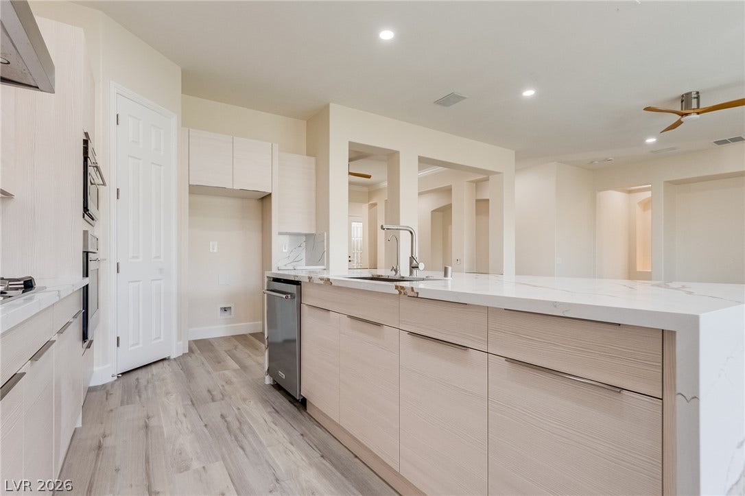 Streamlined cabinetry and waterfall stone countertops define this modern culinary space.