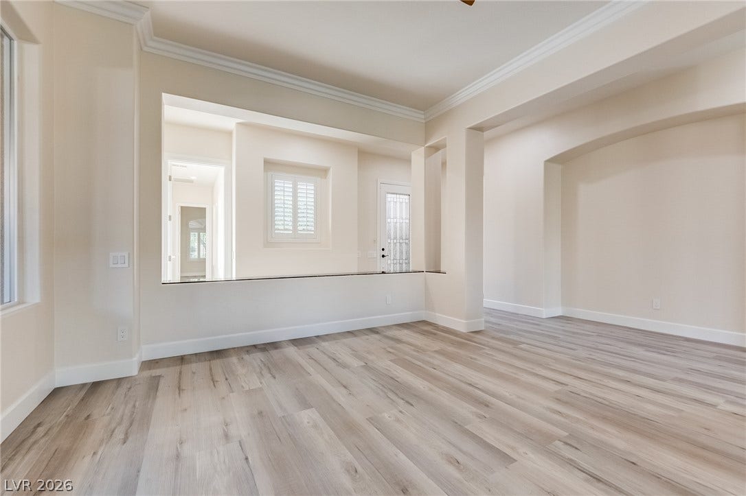 Clean architectural lines, classic crown molding, and modern wood-look floors define this versatile space.