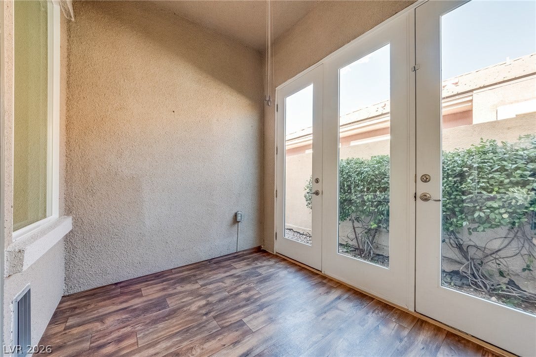 Gleaming wood-look floors complement glass French doors opening to the outdoor garden space.