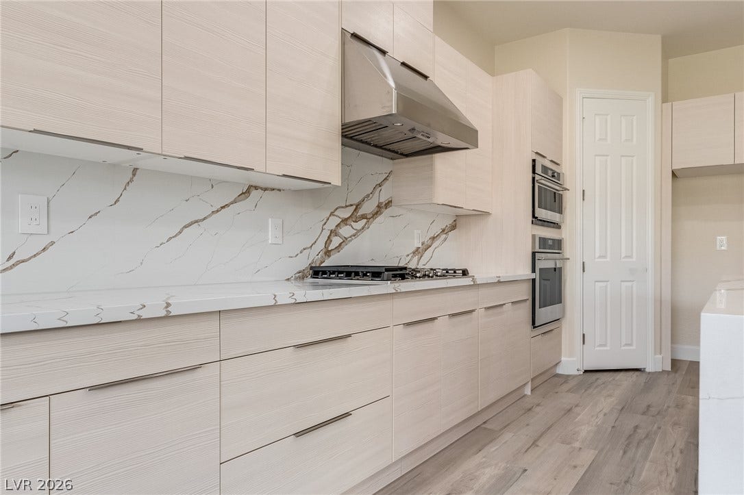 Sleek flat-panel cabinetry and marble-veined quartz countertops line this modern culinary workspace.