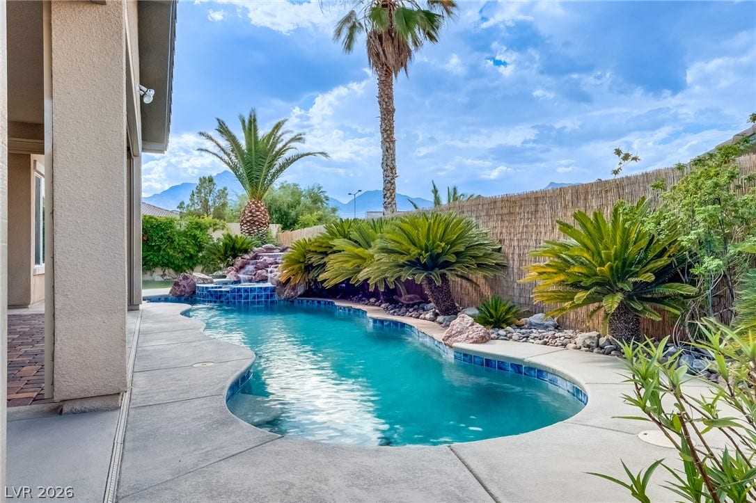 A sparkling in-ground pool is framed by tropical landscaping and mountain views.