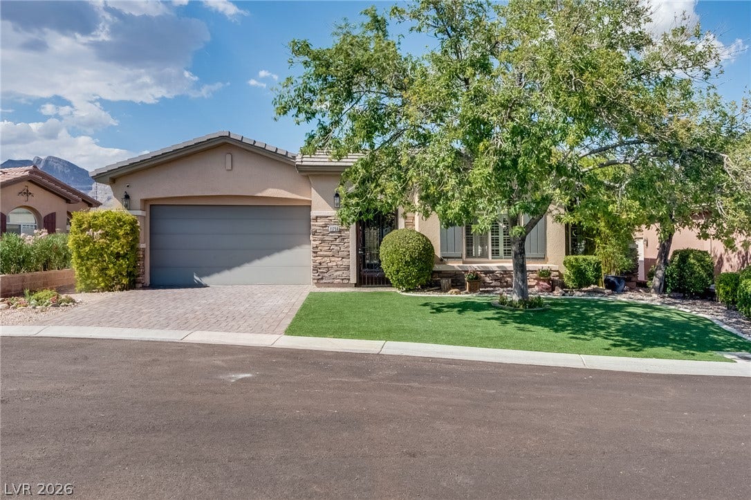Manicured landscaping and stone accents frame this single-story home with an attached garage.