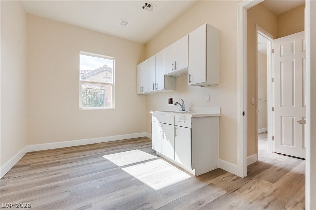 Functional cabinetry and wood-look flooring define this versatile utility space illuminated by natural light.