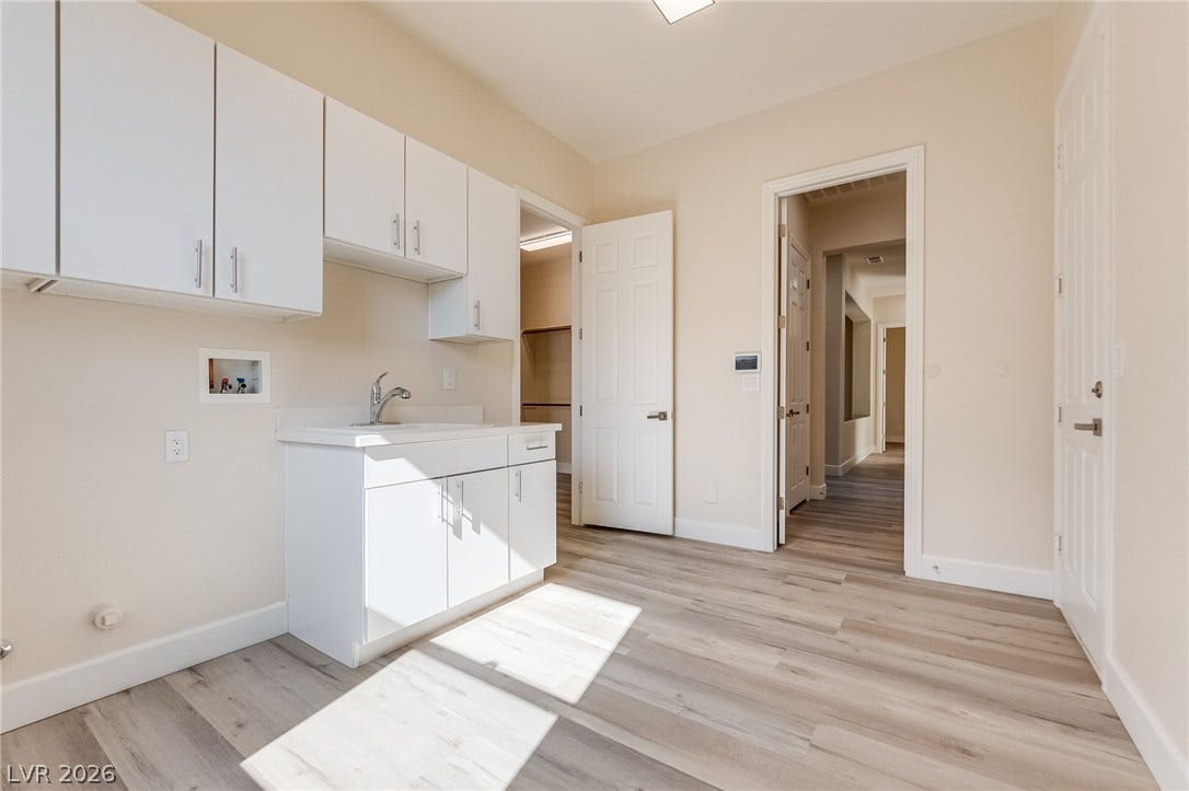 Crisp white cabinetry and durable wood-look flooring define this functional home utility space.