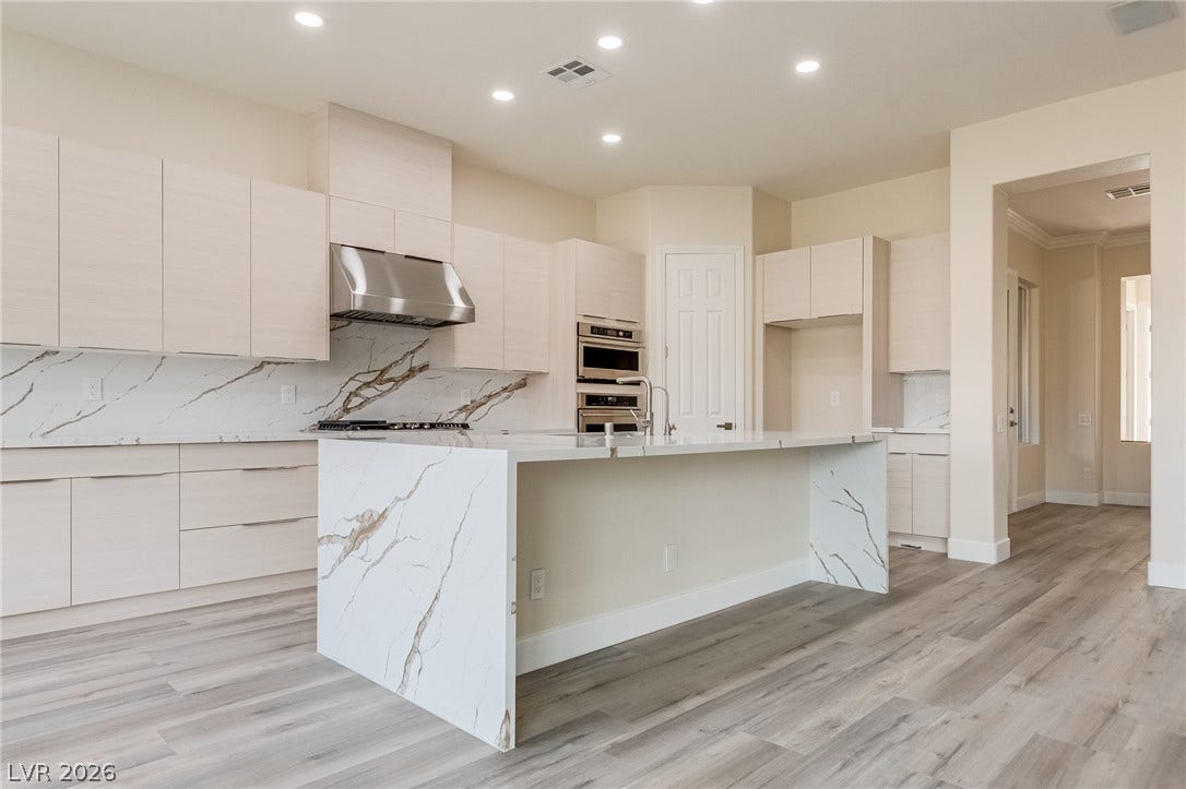 Crisp modern cabinetry paired with waterfall stone countertops anchors this light-filled gourmet space.