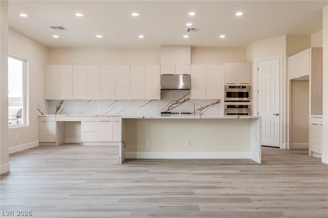 Gleaming wood flooring complements a grand waterfall island in a modern culinary space.