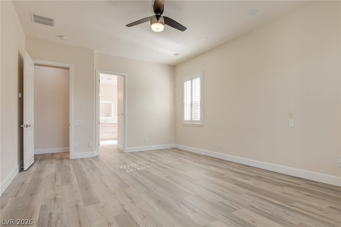 Laminate wood flooring and clean walls create an inviting space with plantation shutters.