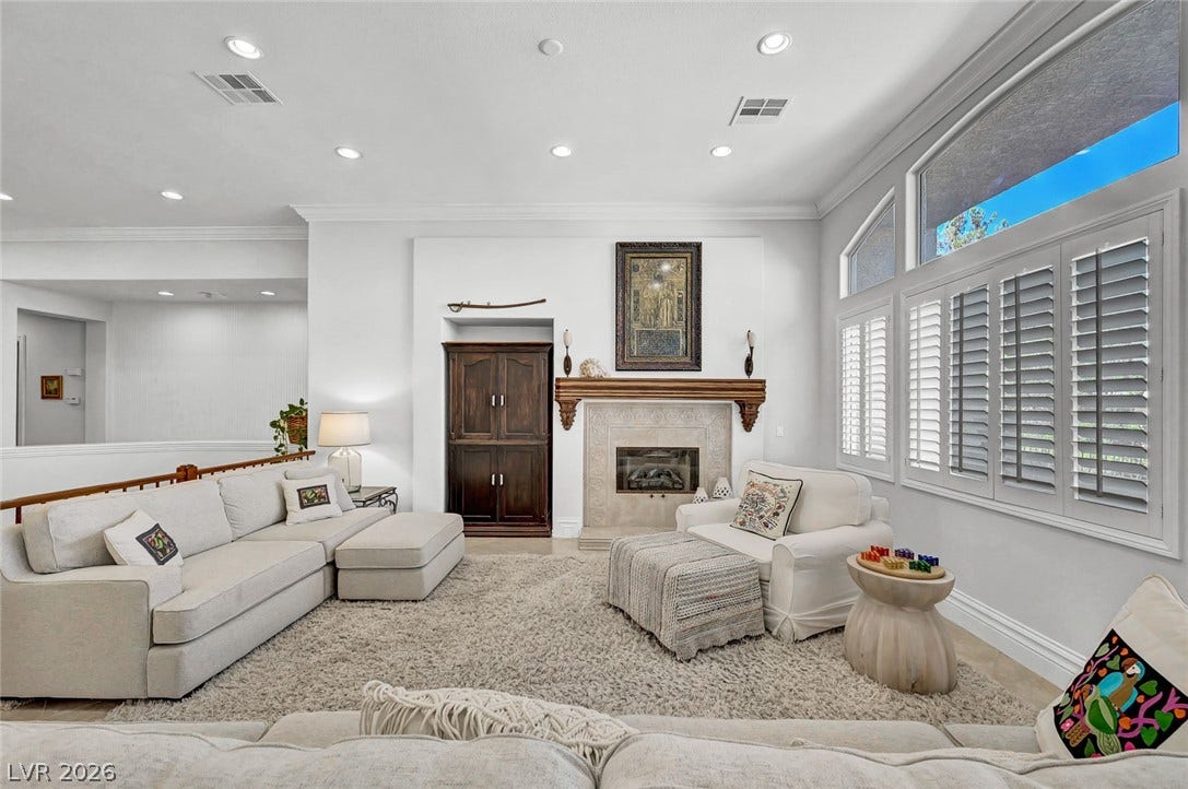 1116 Golden Age Court, Las Vegas, NV 89144 Plantation shutters frame a welcoming living room centered on a gas fireplace.