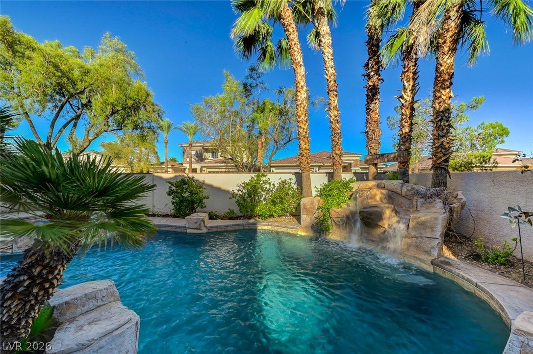 1116 Golden Age Court, Las Vegas, NV 89144 Towering palm trees and a rocky waterfall feature frame this sparkling backyard swimming pool.