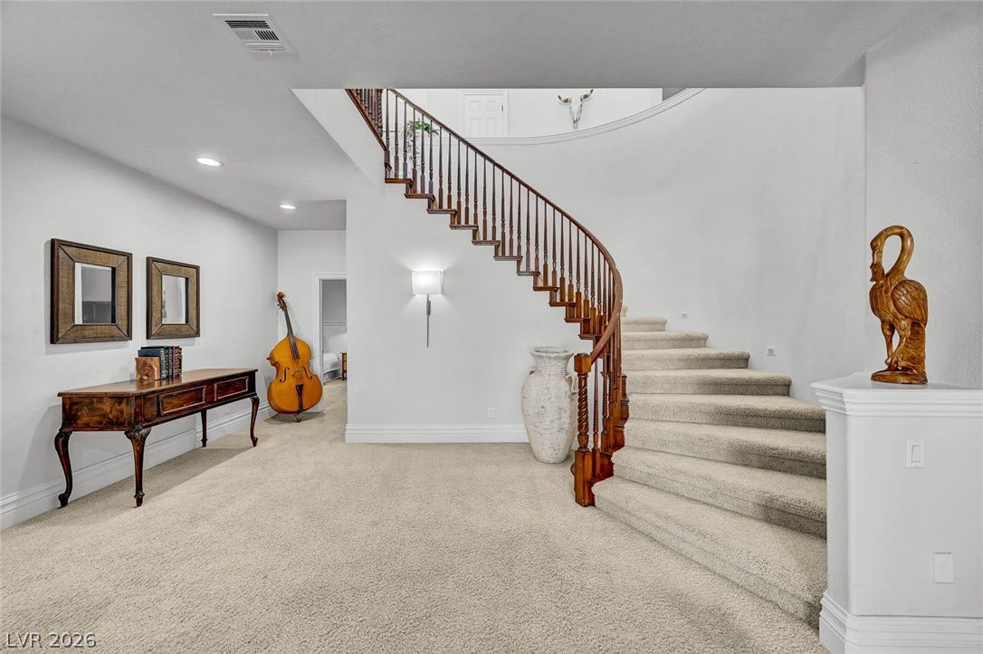 1116 Golden Age Court, Las Vegas, NV 89144 A curved staircase with wooden handrails anchors this carpeted foyer.