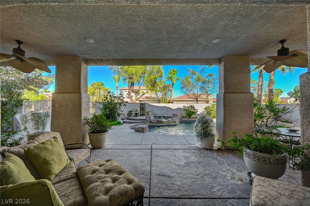 1116 Golden Age Court, Las Vegas, NV 89144 A covered patio overlooking a refreshing backyard pool with integrated stone water features.