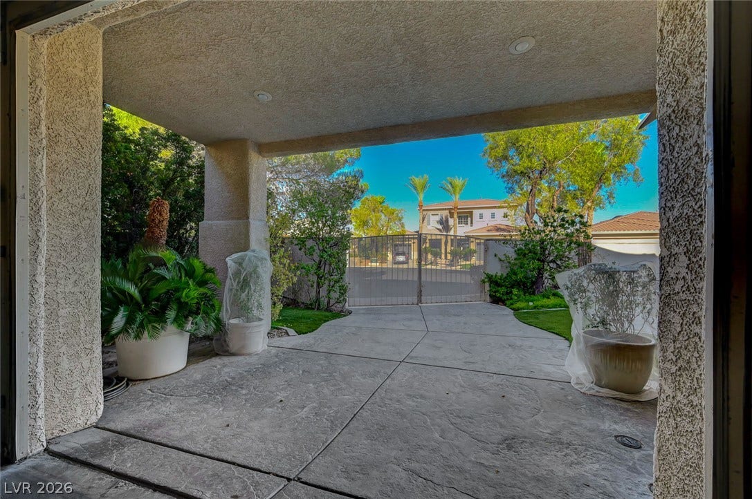 1116 Golden Age Court, Las Vegas, NV 89144 Gated driveway access leads past textured pillars and mature landscaping under a shaded porte-cochere.