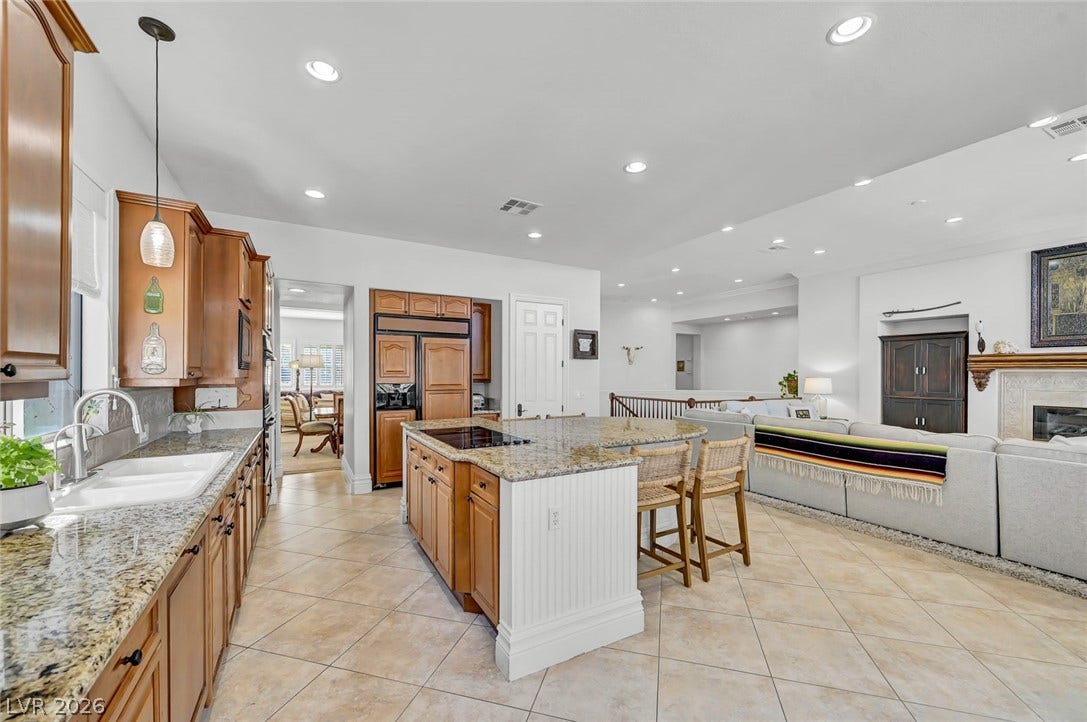 1116 Golden Age Court, Las Vegas, NV 89144 Granite countertops and warm wood cabinetry highlight this open-concept kitchen space.